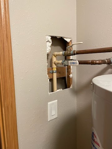 Wall cut open for plumbing access before repair