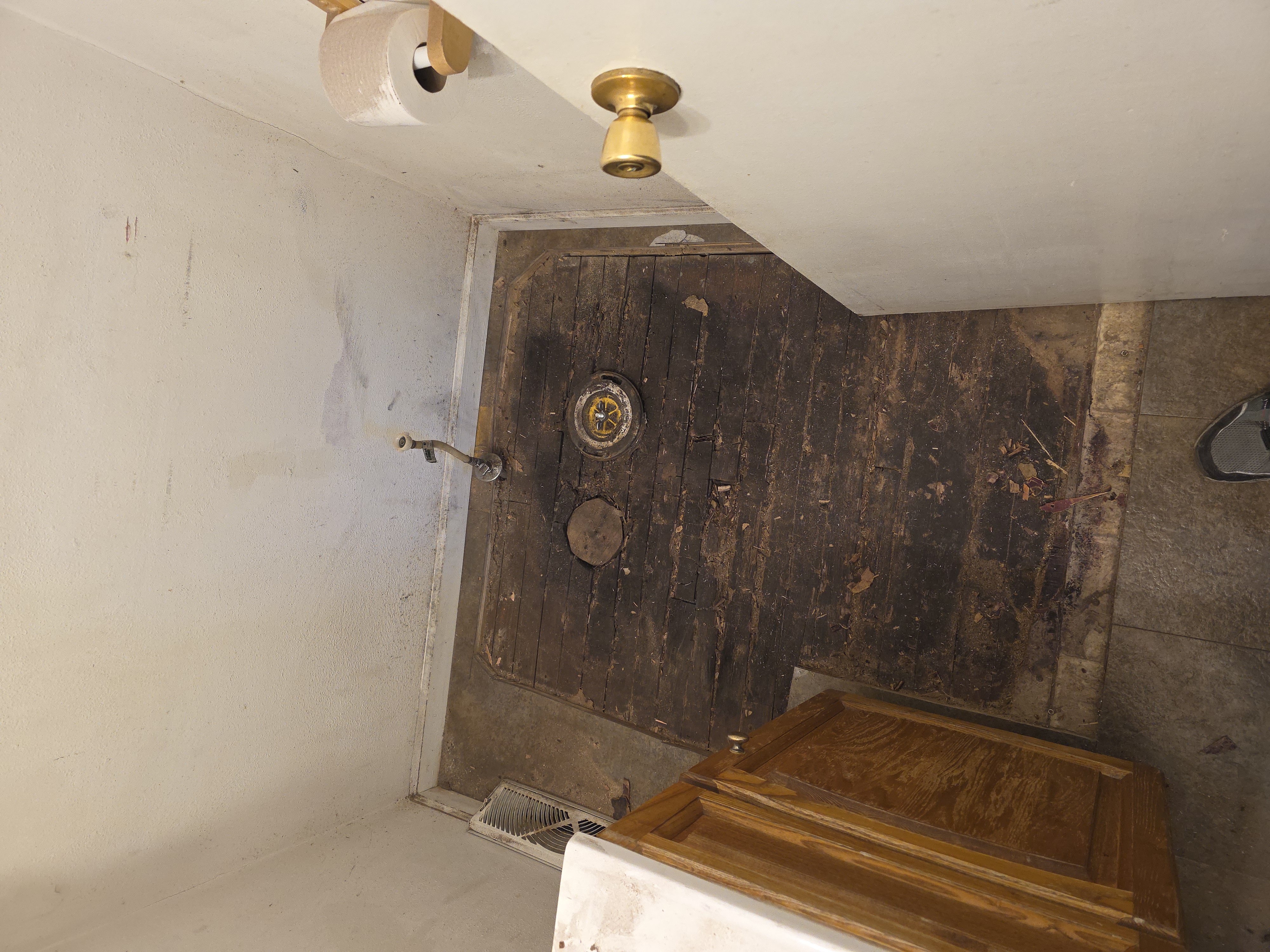 Bathroom floor stripped to bare subfloor before
