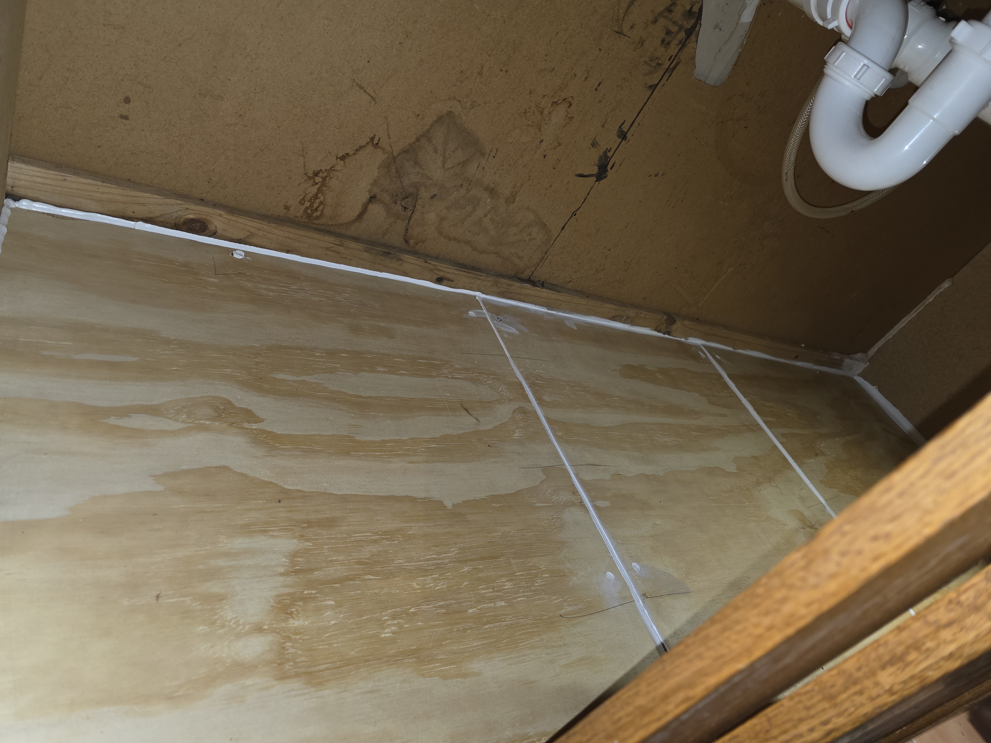 Under-sink cabinet with new floor installed and sealed
